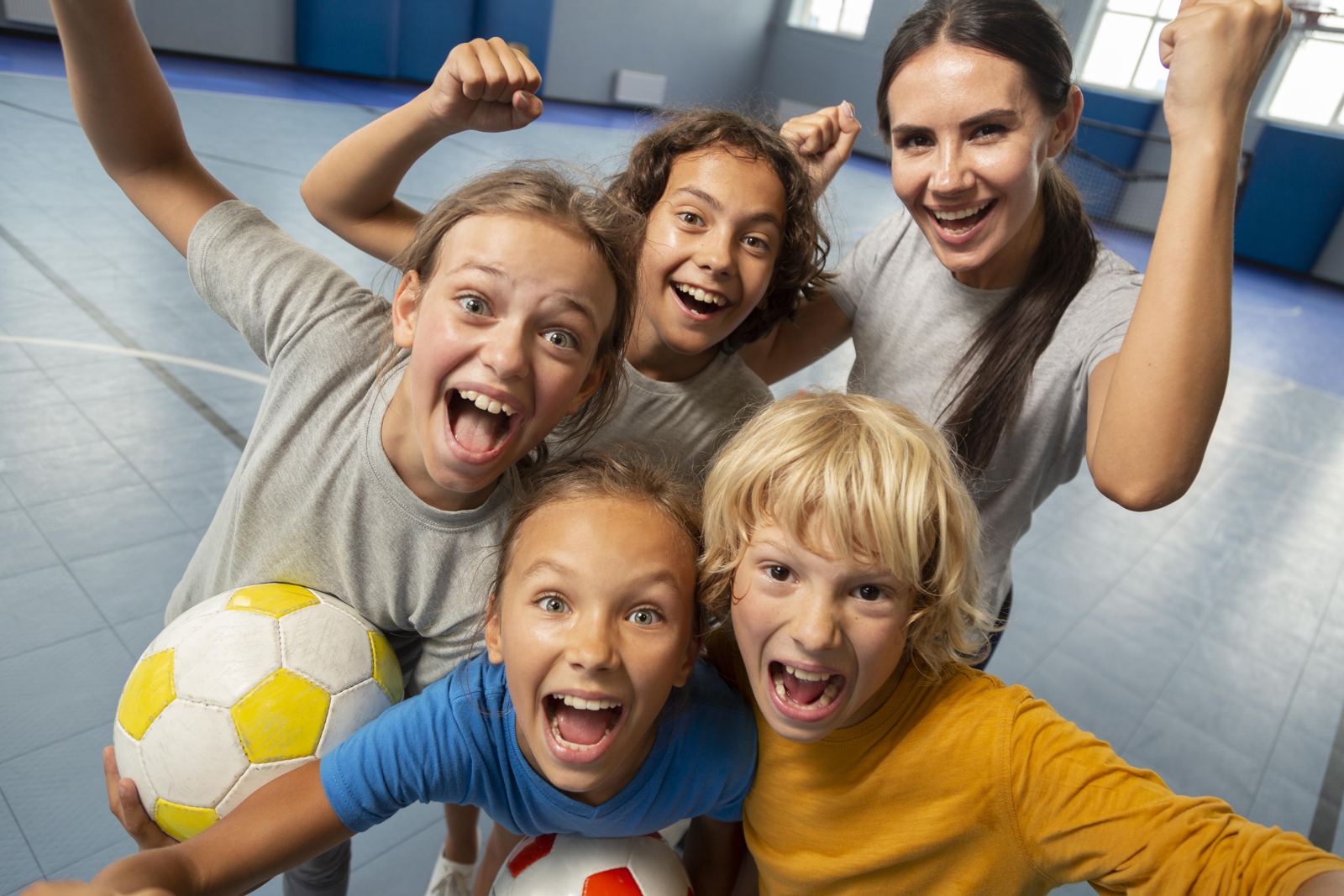 Kindergruppe jubelt in der Halle mit Ball